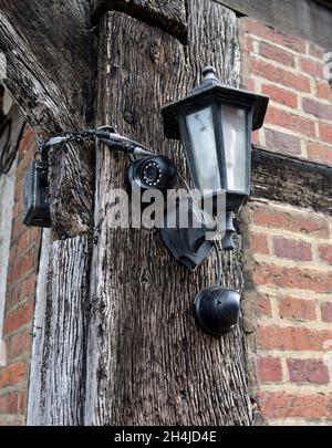 Two outdoor security cameras and wall light mounted on old traditional building timber frame, UK Stock Photo