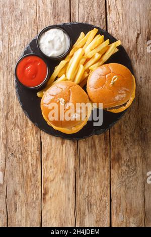 Butter beef burger with French fries close-up on a slate board on the table. Vertical top view from above Stock Photo