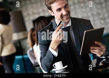 Portrait of a smiling young businessman doing online shopping through computer and credit card Stock Photo