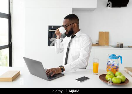 African American man using laptop drinking coffee Stock Photo