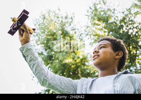 Beautiful happy african american family bonding at the park - Black family having fun outdoors, cute young boy playing with airplane toy Stock Photo