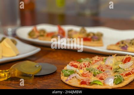 Side angle Selective Focus image of Freshly Baked and sliced pizza along with its ingredients served on table Stock Photo