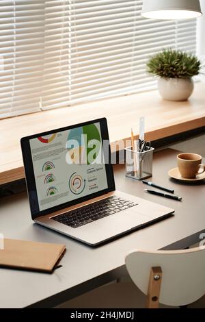 Close-up of laptop with colorful financial graphs on the screen on the table at office Stock Photo