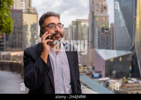 Portrait of handsome Indian businessman in city wearing suit Stock Photo