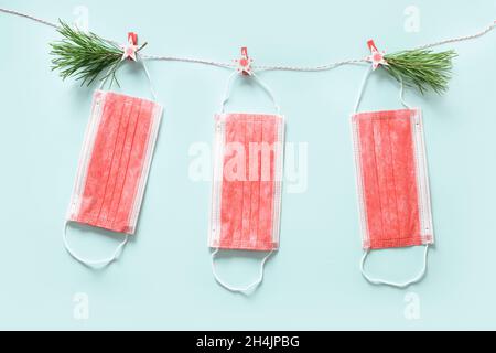 Medical Christmas greeting card with medical face mask on pin decorated fir tree on blue background. Flat lay with copy space for pandemic time. Stock Photo