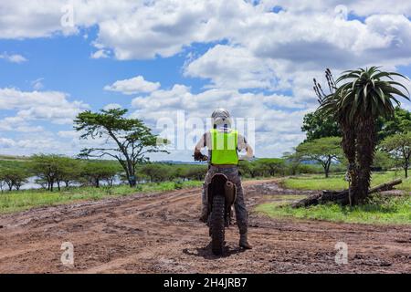 Wildlife wilderness park reserve Ranger unidentified Caucasian on his motorbike doing safety protection patrol from poaching , rear photo on dirt mud Stock Photo