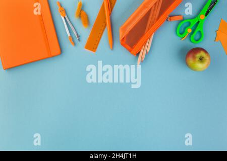 Creative, fashionable, minimalistic, school or office workspace with orange supplies on blue background. Flat lay. Stock Photo