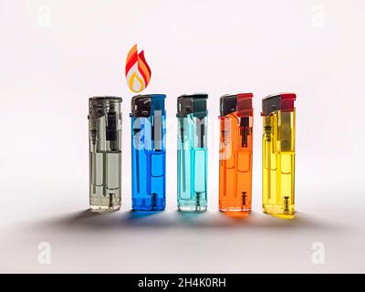 Row of multi coloured disposable lighters and a Conceptual flame Stock Photo