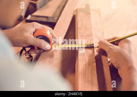 Carpenter measuring a piece of wood in his workshop Stock Photo