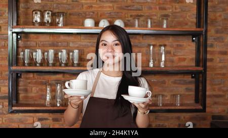Smiling barista holding two coffee cups Stock Photo