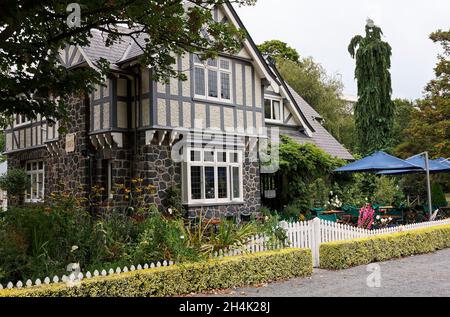 Botanical Gardens; Curator's House now restaurant; stone, stucco, Tudor style, outdoor tables and chairs, umbrellas, 1920, South Island, Christchurch; Stock Photo