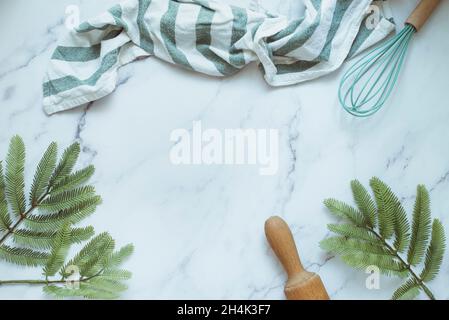 Overhead of a tea towel, rolling pin and silicone whisk on marble worktop Stock Photo