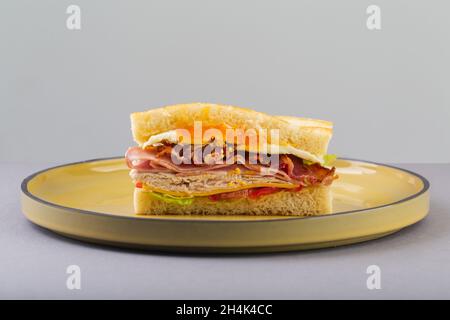 Breakfast sandwich with egg, bacon and vegetables on grey close-up Stock Photo