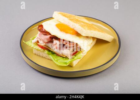 Breakfast sandwich with egg, bacon and vegetables on grey close-up Stock Photo