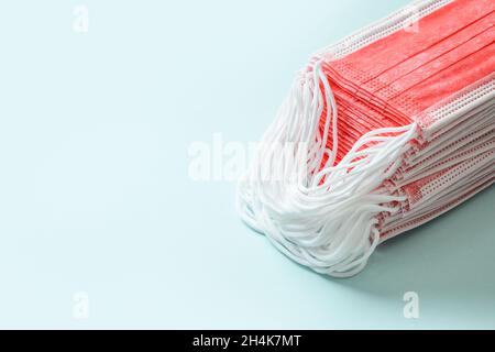 Pile of red medical face mask on a blue background. Stock Photo