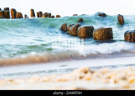 a sea wave beats against a breakwater on a sandy beach, long exposure. Stock Photo