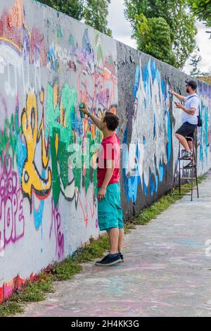 BERLIN, GERMANY - AUGUST 6, 2017: Graffiti artists painting on a section of Berlin wall in Mauerpark. Stock Photo
