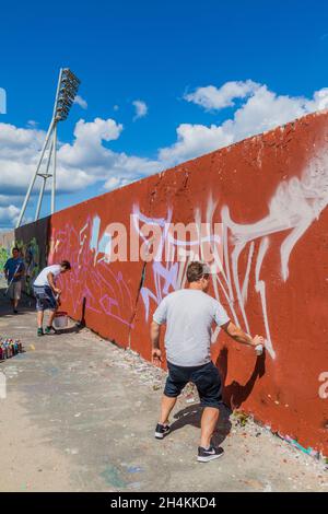 BERLIN, GERMANY - AUGUST 6, 2017: Graffiti artists painting on a section of Berlin wall in Mauerpark. Stock Photo