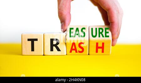 Trash to treasure symbol. Businessman turns cubes and changes the word trash to treasure. Beautiful yellow table, white background. Business, trash to Stock Photo