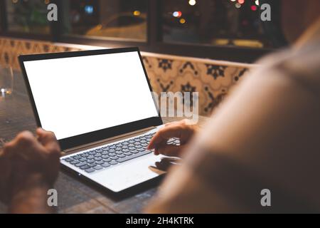 Unrecognizable man working on a laptop with a white screen. Stock Photo