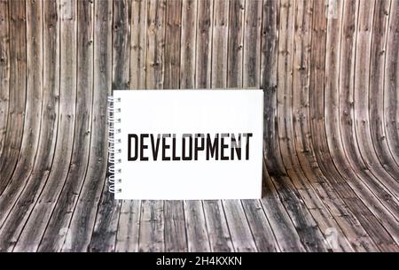 Motivational concept. The word DEVELOPMENT is written on a notepad and a wooden background. Stock Photo