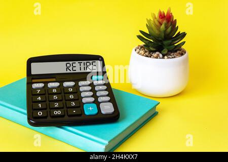 Calculator with the word RETIRE on the display. On a yellow background, a cactus and a green notepad Stock Photo