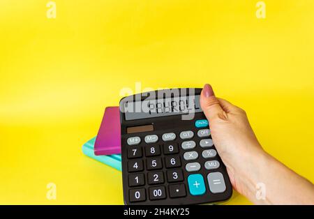 Female hand holds calculator with text on display PAYROLL, on yellow background Stock Photo
