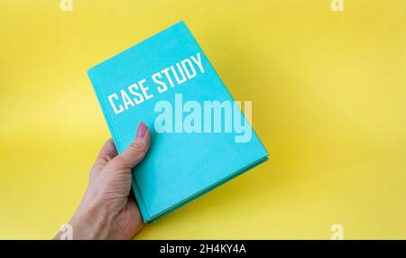 Case Study text on a green notebook in a female hand on a white background. Stock Photo