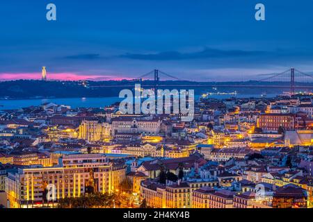 The lights of Lisbon in Portugal with the Sanctuary of Christ the King and the 25 de Abril Bridge Stock Photo