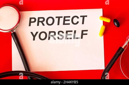 On a white sheet of paper the text protect yourself, near a stethoscope on a red background Stock Photo