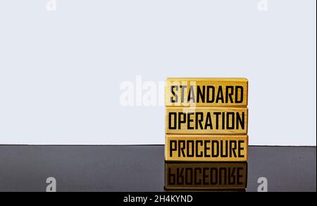 A text symbol showing standard operating procedure. Text on wooden blocks and on a black mirror table .Conceptual photo Stock Photo