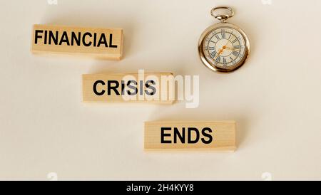 On wooden blocks the text End of crisis and a clock on a white background Stock Photo