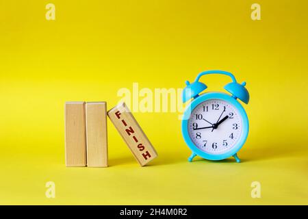 Blocks with the text FINISH on a yellow background, next to a blue alarm clock Stock Photo