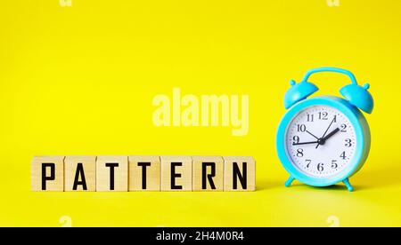 The word PATTERN is written on wooden blocks and on a yellow background, next to an alarm clock Stock Photo