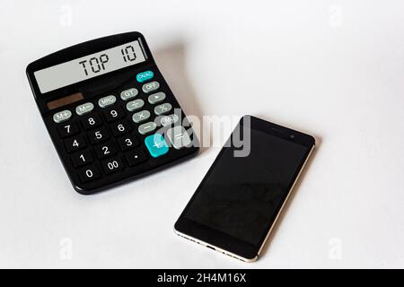 The calculator display reads TOP 10. A telephone lies on a white background Stock Photo