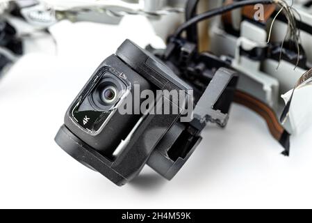 Macro shot of the 4k lens on a damaged drone after a fall with broken cables, isolated on a white background. Stock Photo