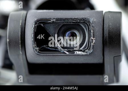 Macro shot of the 4k lens on a damaged drone after a fall with broken cables, isolated on a white background. Stock Photo