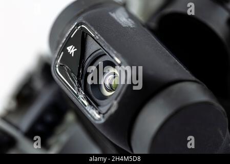 Macro shot of the 4k lens on a damaged drone after a fall with broken cables, isolated on a white background. Stock Photo