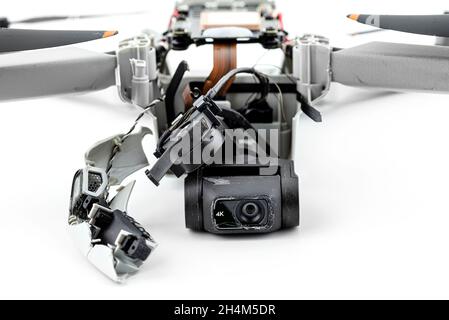 A broken drone after a fall with torn cables and a broken camera, isolated on a white background. Stock Photo