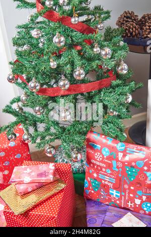 Christmas presents. packages wrapped with colored paper on the ground under the Christmas tree decorated with silver balls and red ribbon and decorati Stock Photo
