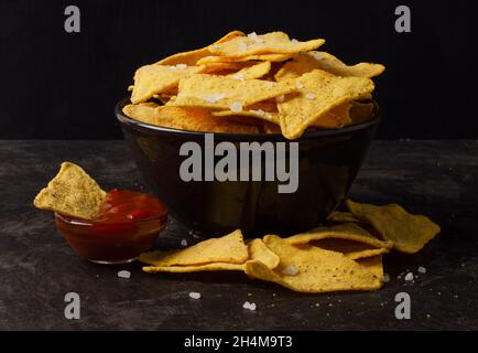 Mexican corn chips nachos with tomato sauce, salsa dip on a dark background Stock Photo