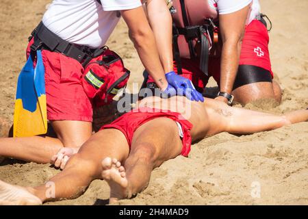 Red Cross lifeguards rescue simulation and CPR on beach in Spain. Stock Photo