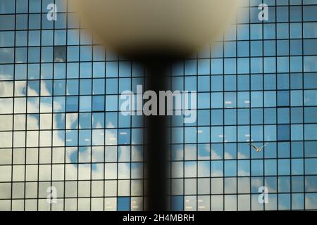 An office building is seen in Warsaw, Poland with square, reflective windows and an out of focus street light in the foreground. Stock Photo