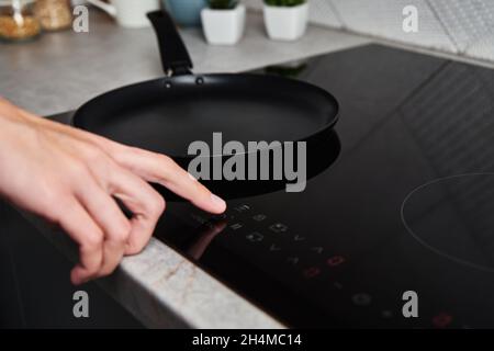Modern kitchen appliance. Woman hand turn on induction stove to cook. Finger touching sensor button on induction or electrical hob Stock Photo