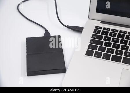 External hard drive connect to laptop computer, transfer or backup data between laptop and hard disk close-up Stock Photo