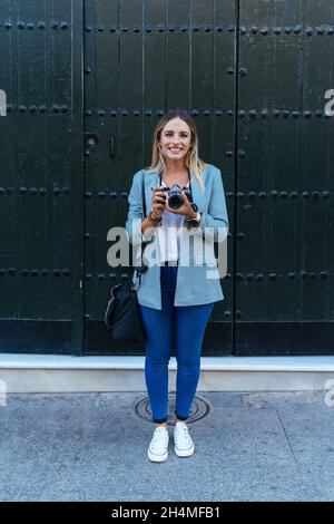 Delighted woman with retro camera in city Stock Photo