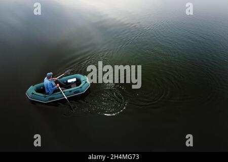 Top view of a lone fisherman on a boat in the early morning fishing on the lake. Stock Photo