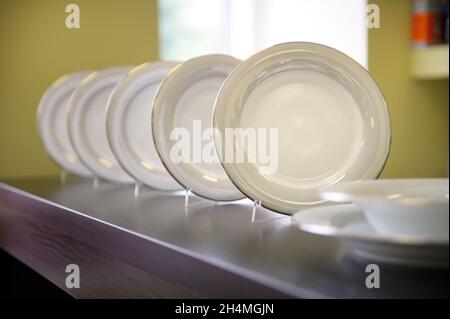 there are many white ceramic plates on the shelf. Stock Photo
