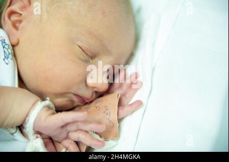 a newborn baby on the first day of its birth in the maternity hospital. Stock Photo