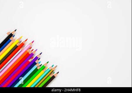 Space for creativity: 23 colored wooden crayons against white background. Stock Photo